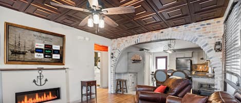 A living room with a fireplace, leather sofa, and a ceiling fan.