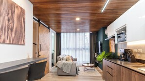 A modern living room with a sofa, a coffee table, and a kitchen area with cabinets and a countertop. - Manila Luxury Suites 201 (Medellín)