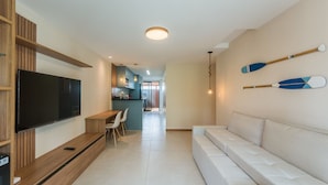A modern living room with a flat-screen TV, wooden entertainment unit, and a sofa.