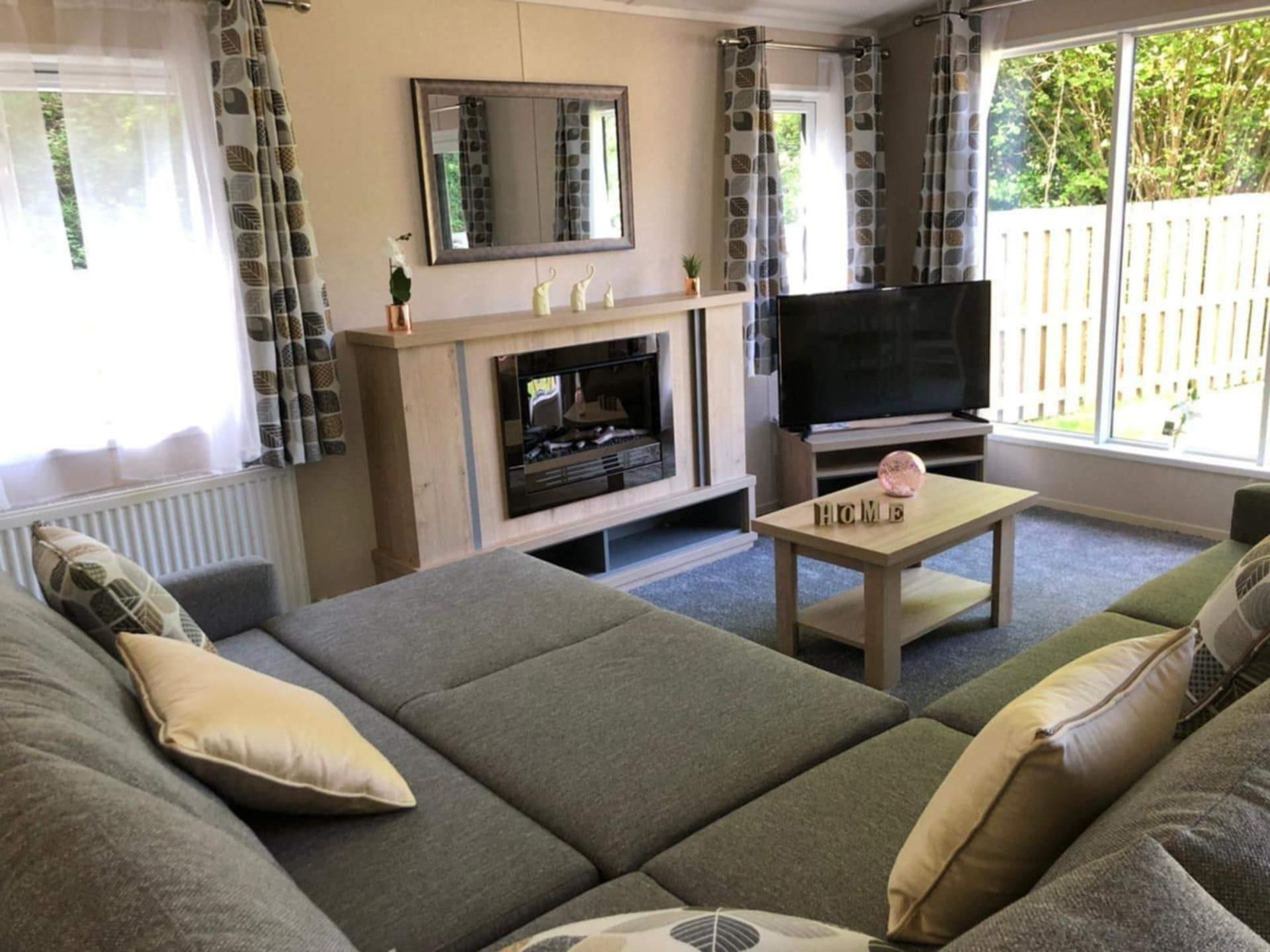 A living room with a sofa, a fireplace, a TV, and a window with curtains.