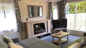 A living room with a sofa set, a television, and a fireplace. - Hoburne Devon Bay Woodland Glade 5 (Paignton)