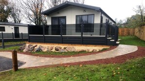 A modern two-story house with a covered porch and a stone foundation. - Hoburne Devon Bay Woodland Glade 5 (Paignton)