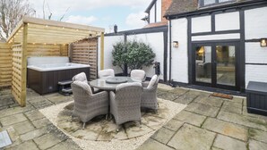 Une terrasse dotée d’un jacuzzi, de fauteuils en osier et d’une pergola en bois.