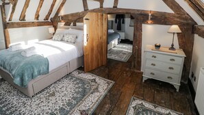 Une chambre à coucher avec un grand lit, une table de chevet, une commode et un plafond en bois.