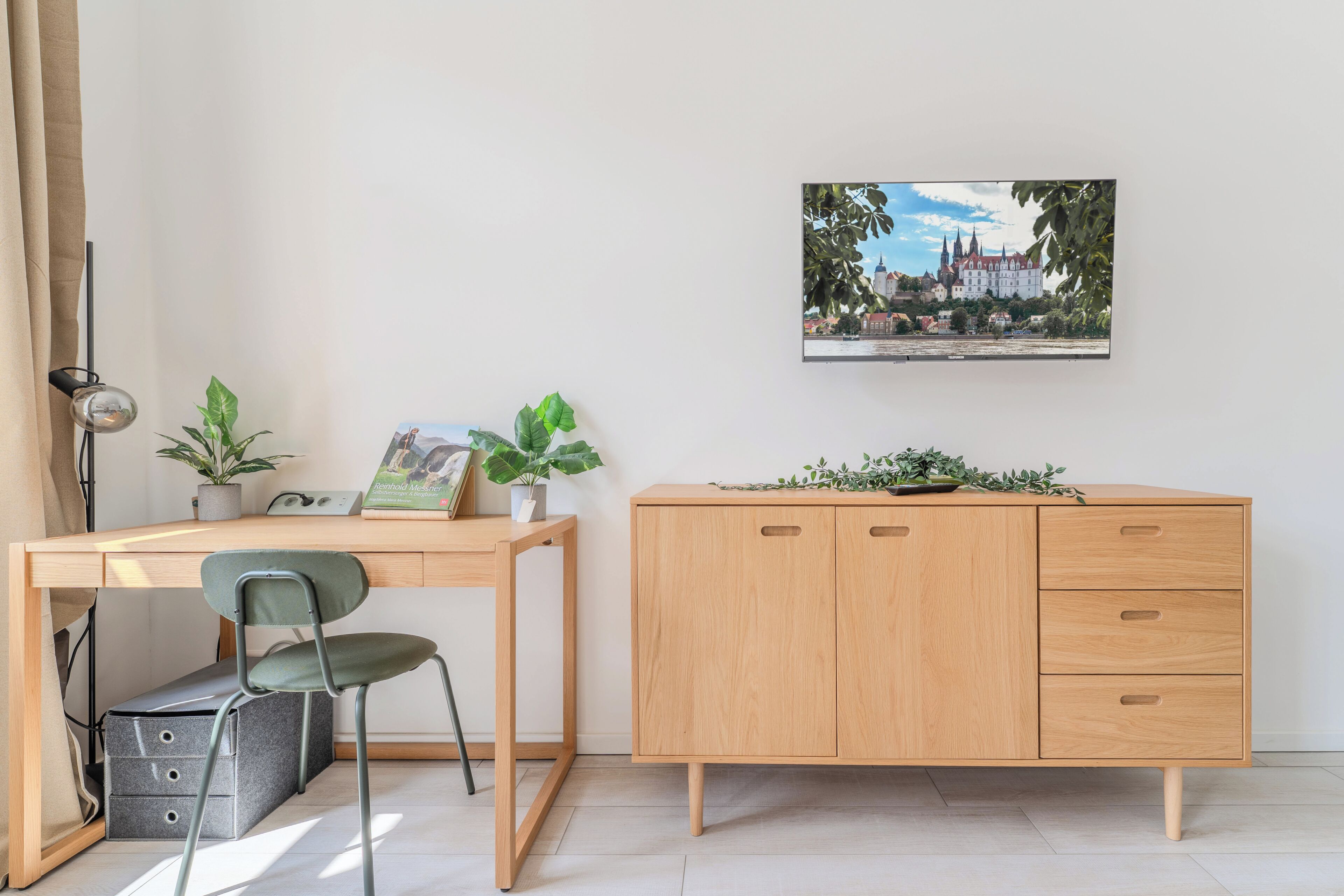 Ein Zimmer mit einem Holztisch, einem Stuhl, einem Schrank und einem gerahmten Bild an der Wand.