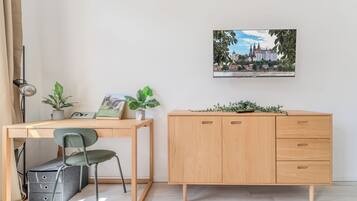 Ein Zimmer mit einem Holztisch, einem Stuhl, einem Schrank und einem gerahmten Bild an der Wand.