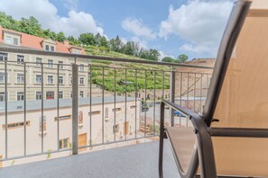 Un balcó amb barana metàl·lica que dona a una zona residencial amb edificis i vegetació.