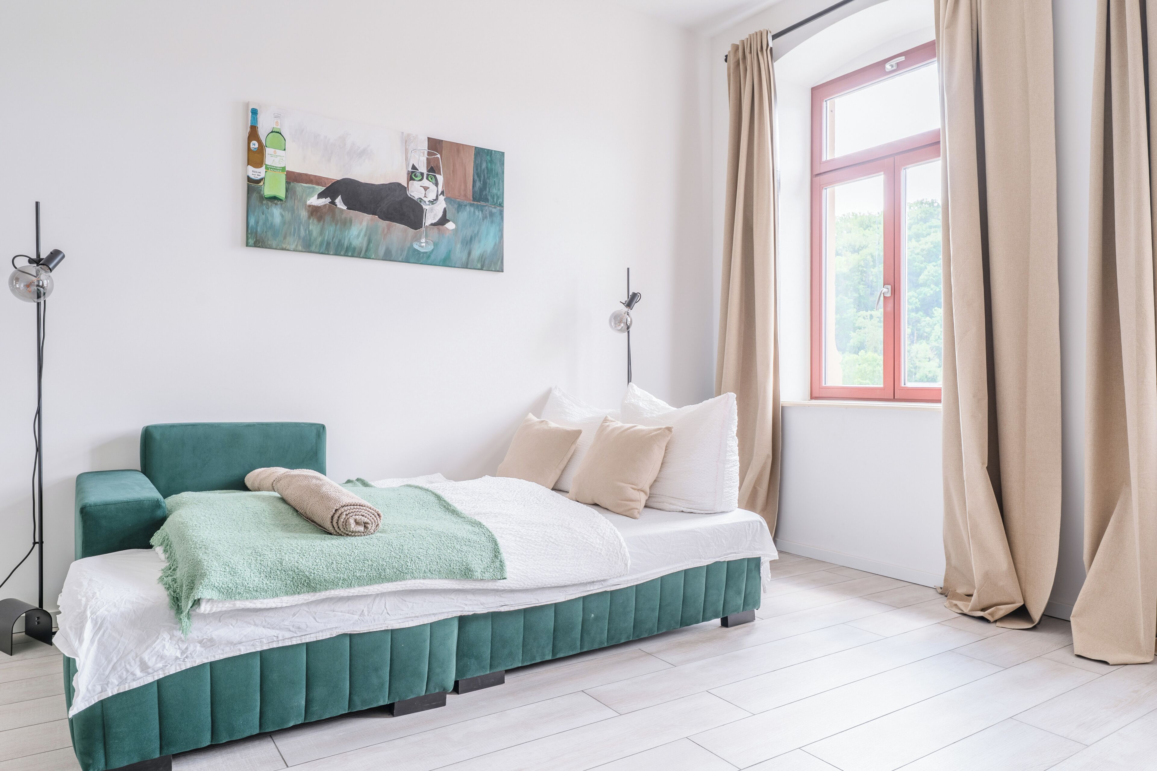 Une chambre à coucher avec un lit, un tableau, une fenêtre et des rideaux.