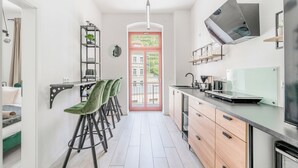 A modern kitchen with a dining area, a built-in oven, and a view through the door.