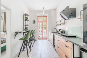 Una cuina moderna amb zona de menjador, forn de mur i vista per la porta.