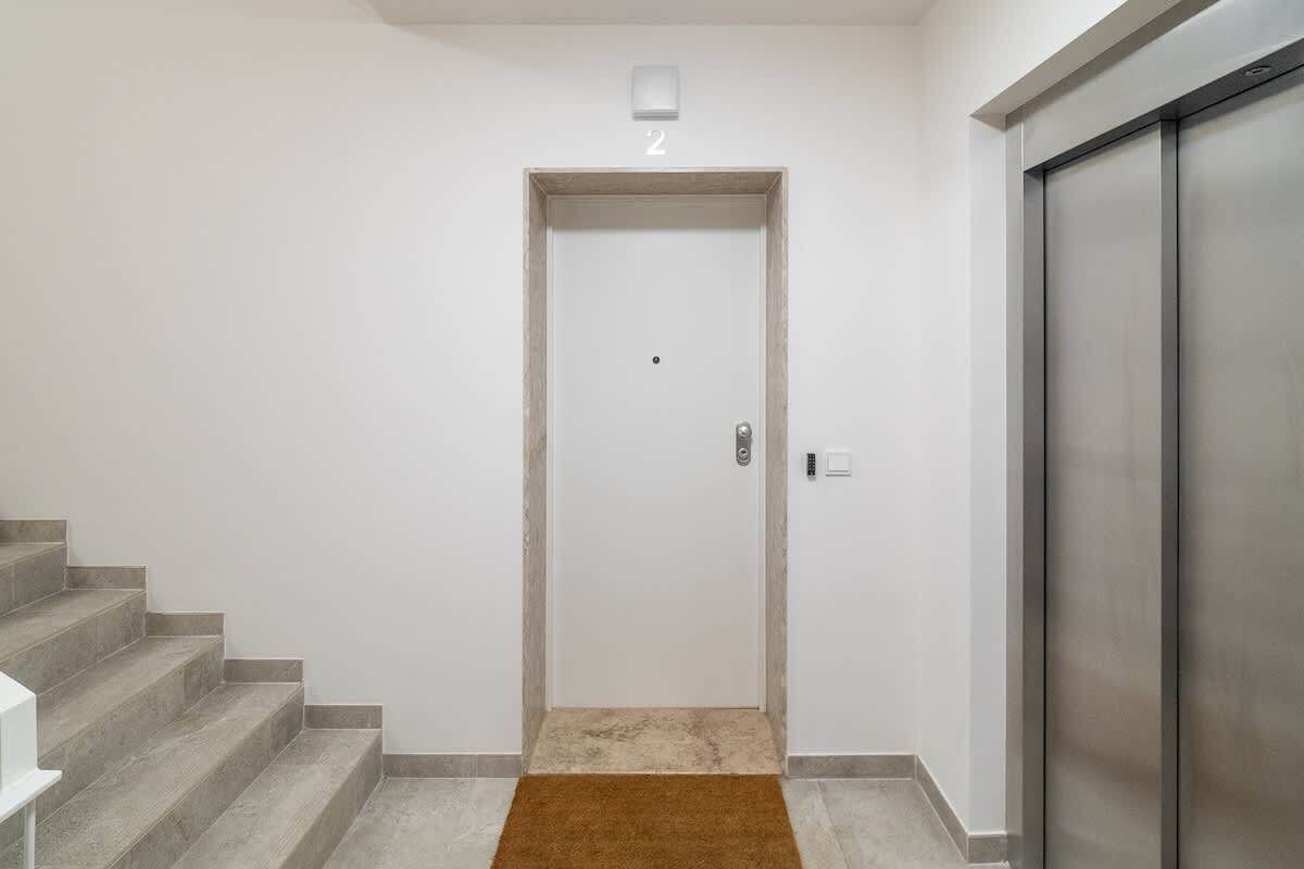 Un corridoio con una porta contrassegnata dal numero 2, una scala a sinistra e un ascensore a destra.