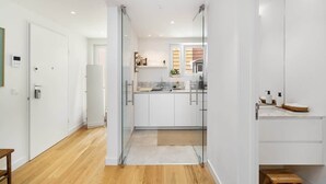 A modern kitchen with white cabinets, a central island, and a glass partition. - Stylish Apartment w/ River View & Terrace (Lisbon)