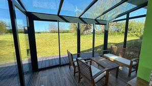 Ein Wintergarten mit Holzterrasse, einem Tisch und einer Bank.