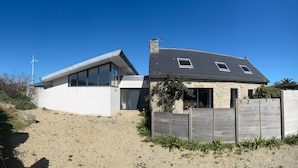 Ein modernes Haus mit geneigtem Dach, einem großen Glasfenster und einer Stein-Fassade.