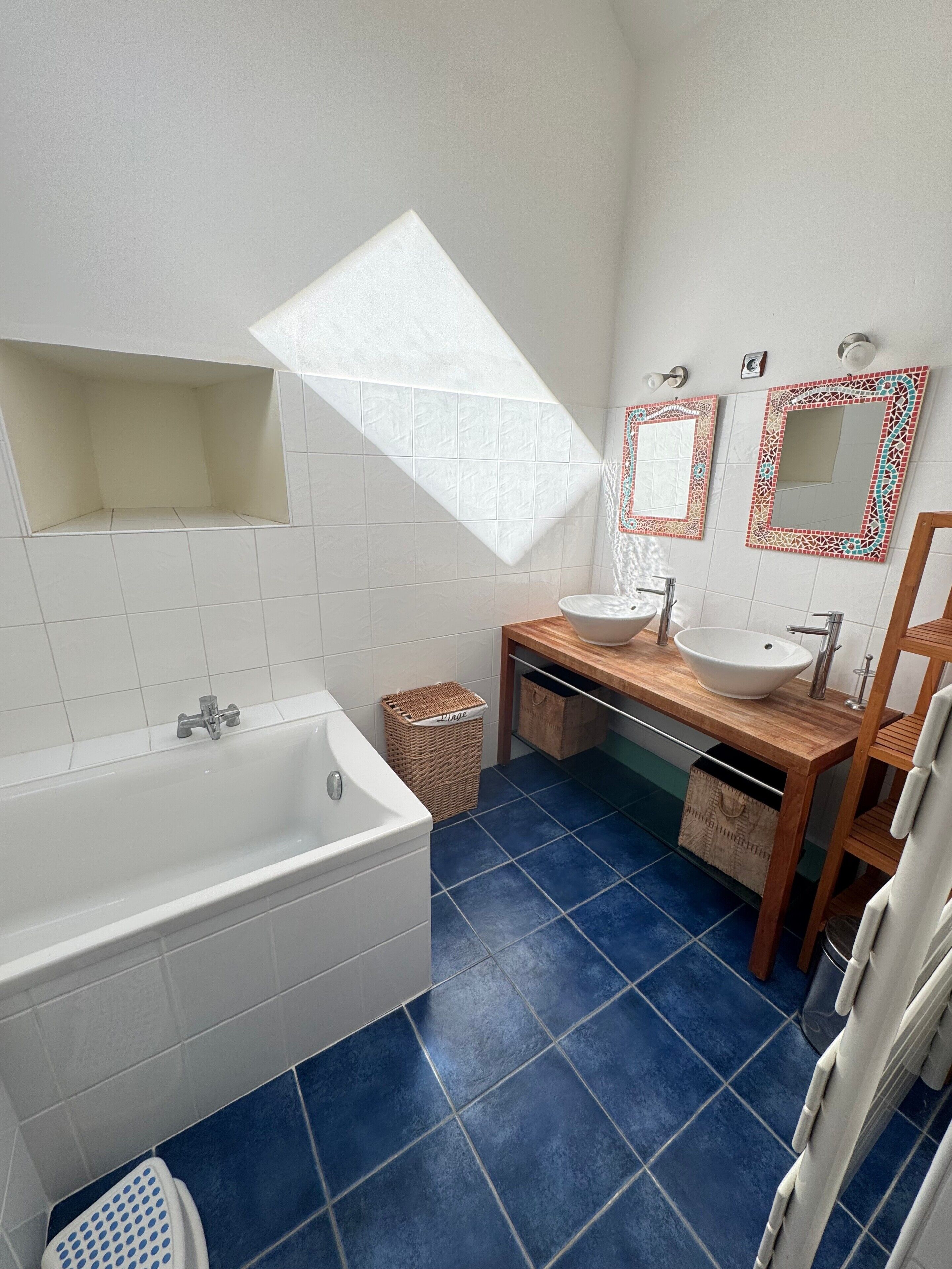 A bathroom with a bathtub, a sink, a mirror, and a window.