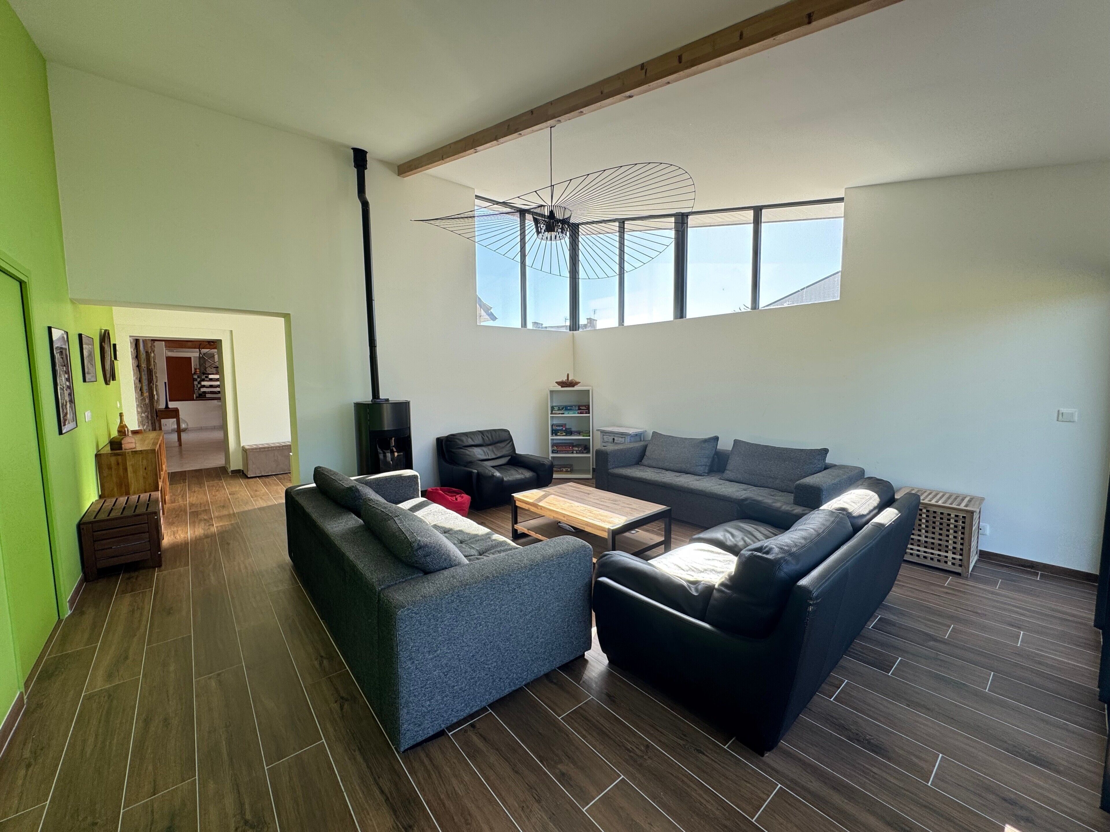 Un salón amplio con un gran ventanal, chimenea y un moderno ventilador de techo.