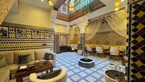 A spacious living area with a high ceiling, patterned walls, and a balcony with plants. - Riad Safia (Rabat)
