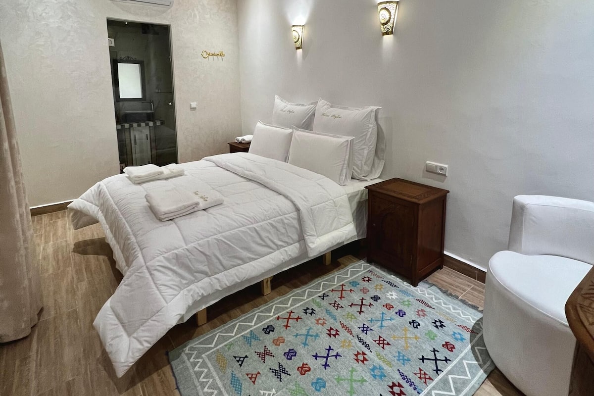 A bedroom with a bed, bedside tables, a rug, and a ceiling fan.