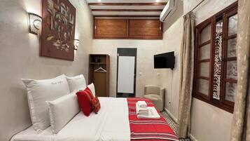 A hotel room with a bed, a wardrobe, a television, and a window with curtains.