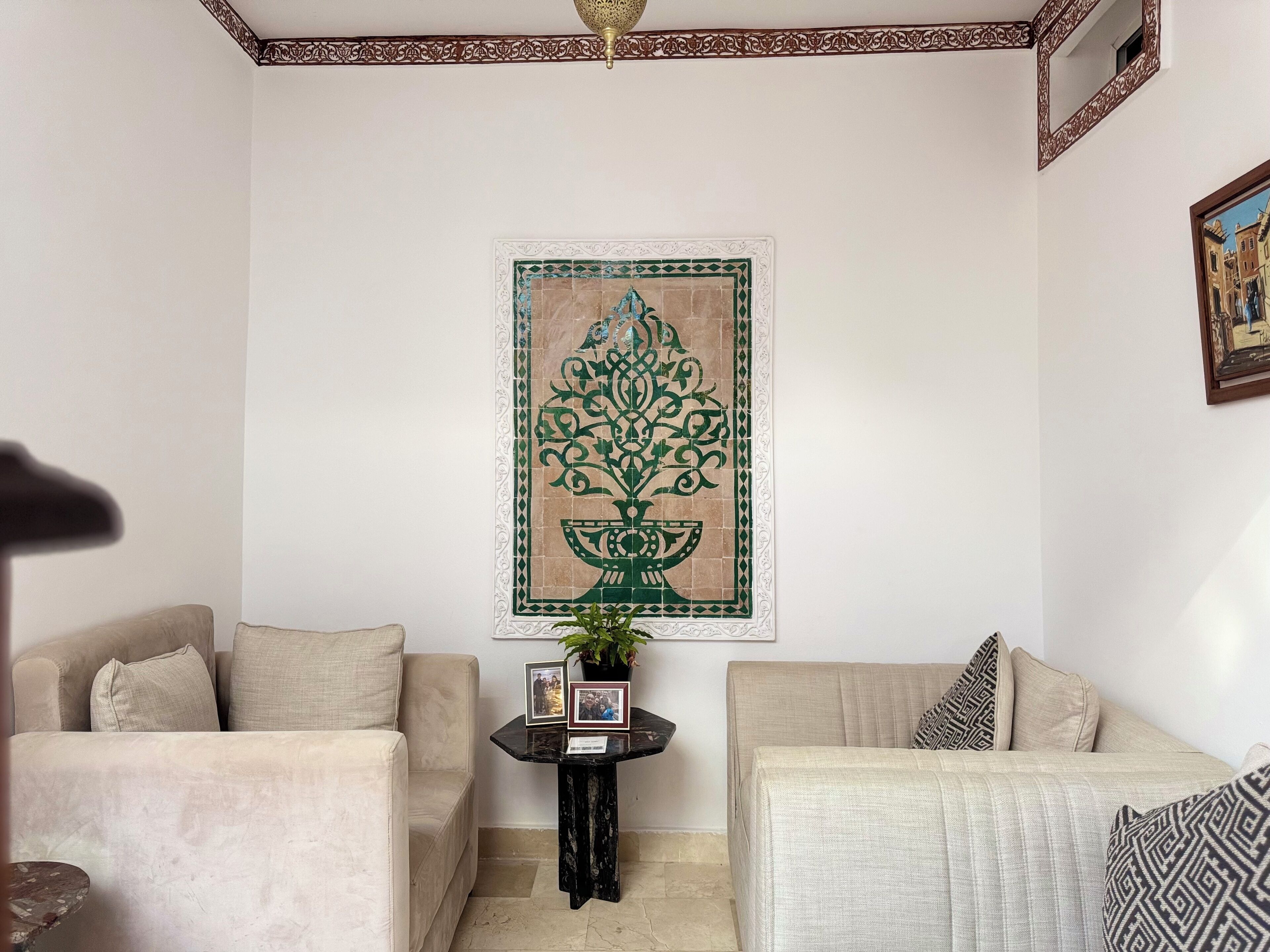 A living room with two sofas, a small table with a plant, and a decorative wall piece.
