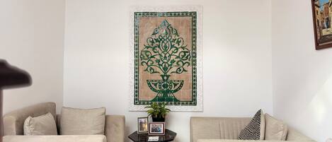A living room with two sofas, a small table with a plant, and a decorative wall piece.