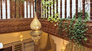 A wooden staircase with intricate carvings and a hanging light fixture. - Riad Safia (Rabat)