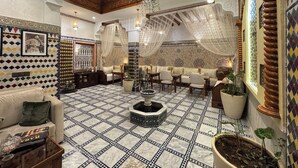 A spacious lounge with a high ceiling, patterned floor tiles, and a central fountain. - Riad Safia (Rabat)