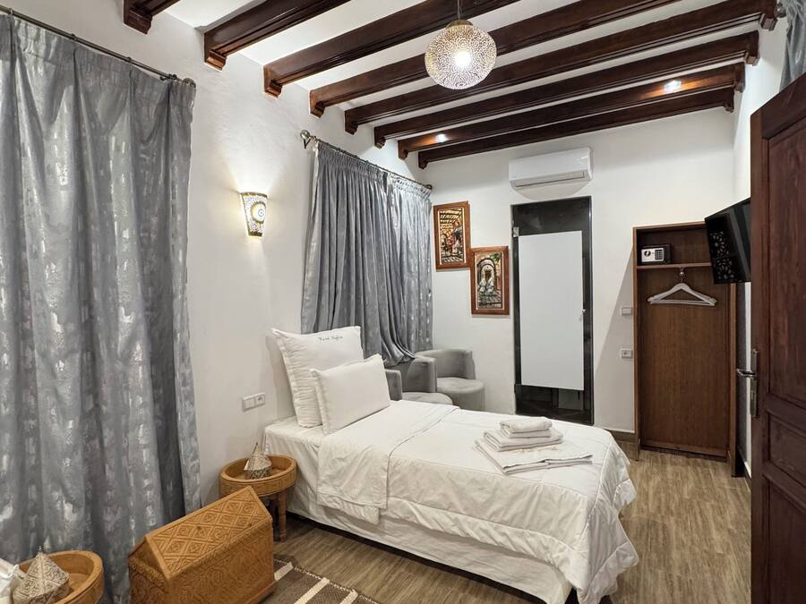 Un dormitorio con cama, cabecera de madera, lámpara colgante, espejo y armario.
