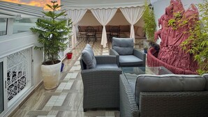 A rooftop terrace with outdoor seating, a large potted plant, and a decorative rock feature. - Riad Safia (Rabat)