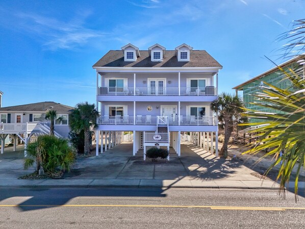 Un hôtel de deux étages situé en bord de mer, doté d’un balcon au deuxième étage, d’une allée couverte et d’un espace de stationnement à l’avant.