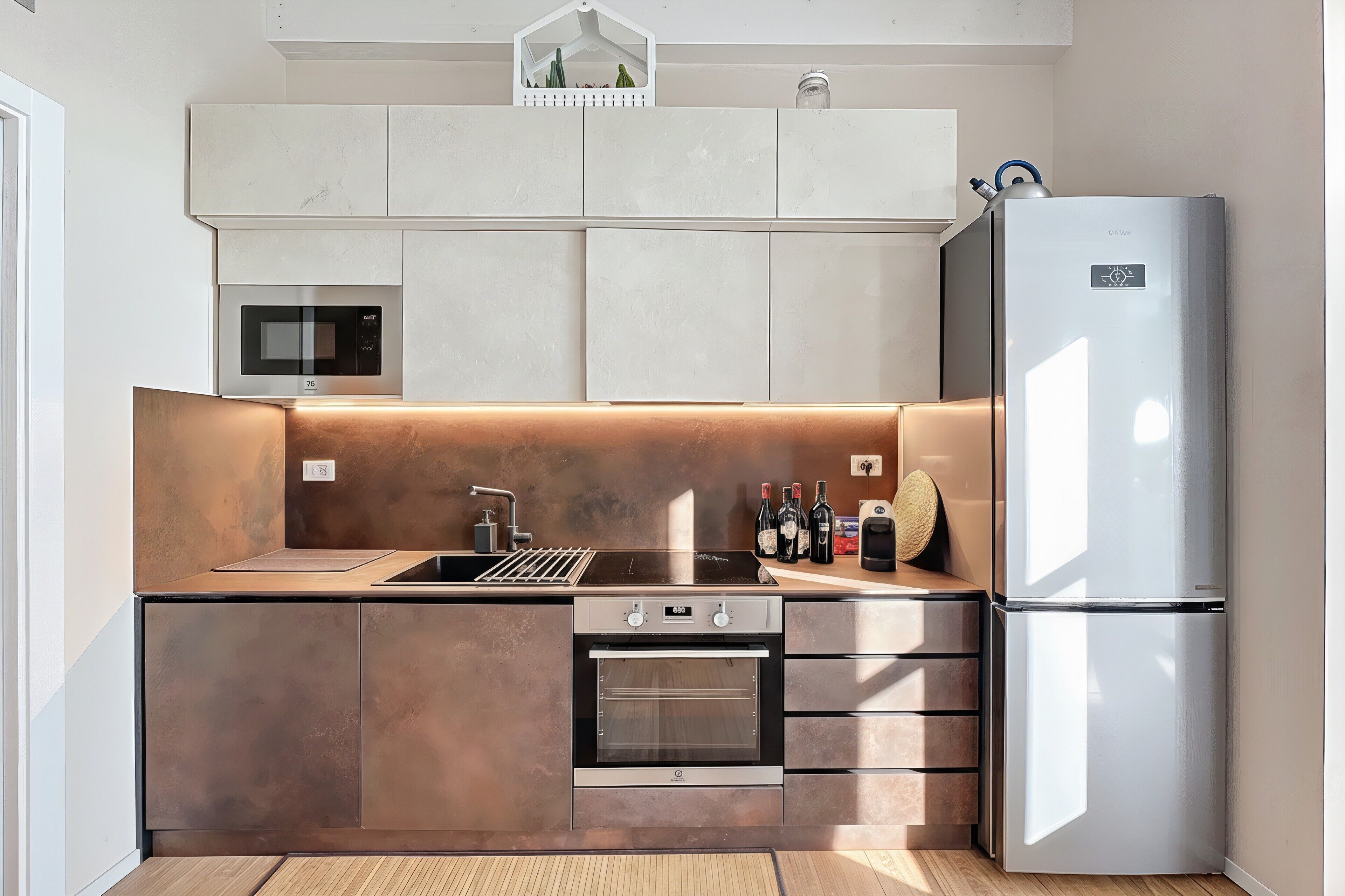 Une cuisine moderne dotée d’un four, d’un micro-ondes et d’un réfrigérateur encastrés, avec un design épuré et un grand espace de travail.