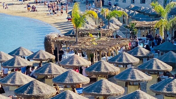 A beach with thatched umbrellas and lounge chairs, a pool area, and a building in the background. - Holiday Home 'Villa Traimari' with Sea View, Wi-Fi and Air Conditioning (Trani)