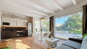 A modern living room with a sofa, a dining table, and a kitchen area with a microwave. - Holiday Home 'Villa Traimari' with Sea View, Wi-Fi and Air Conditioning (Trani)