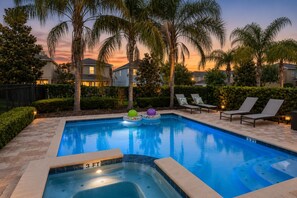 A swimming pool with lounge chairs and a hot tub, surrounded by palm trees and houses. - Casa Encore Resort/Piscina privativa/5 Quartos (Kissimmee)