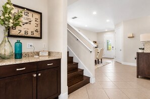 A kitchen with dark wooden cabinets, a clock, and a vase with flowers. - Casa Encore Resort/Piscina privativa/5 Quartos (Kissimmee)