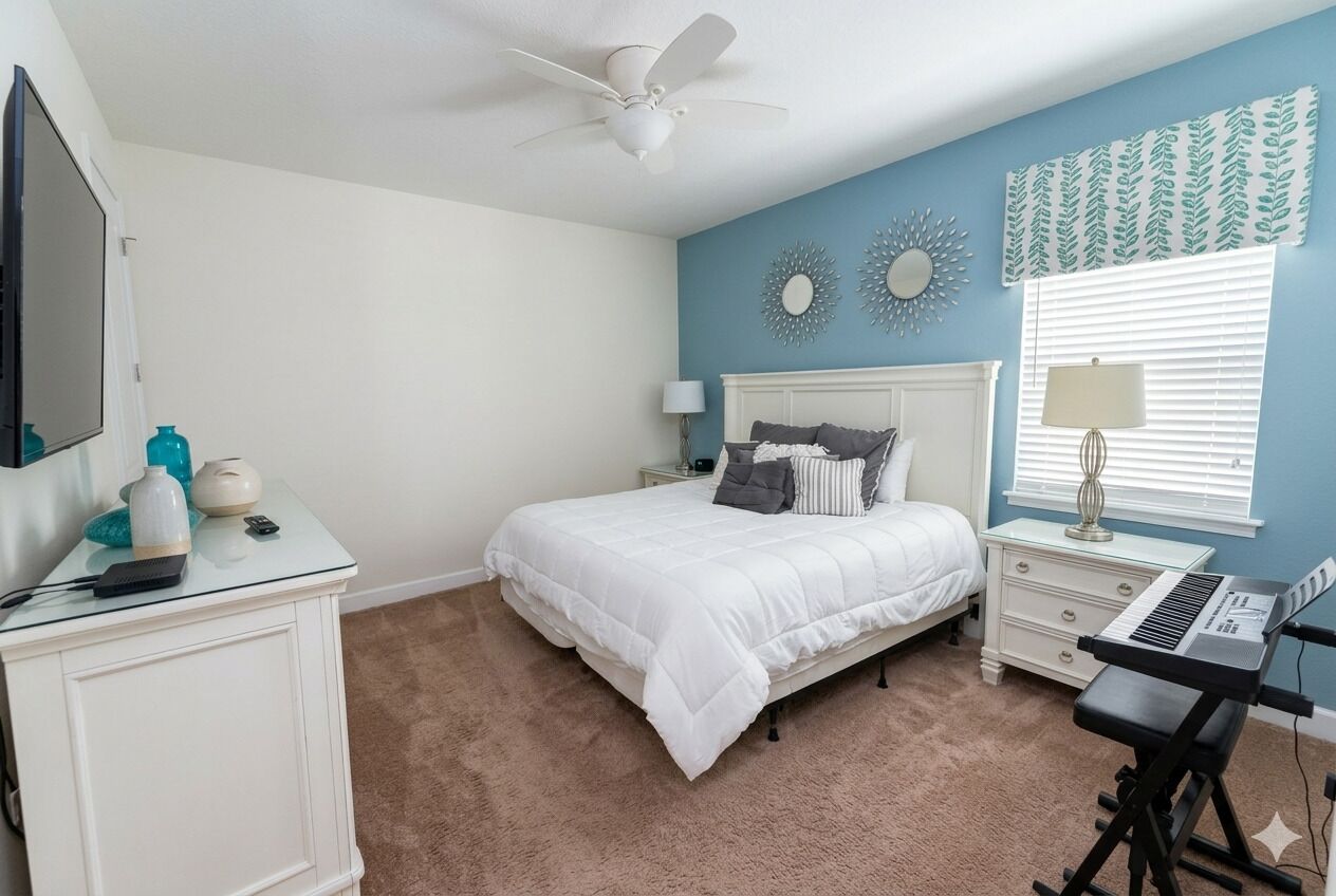 A bedroom with a bed, a desk, a chair, a ceiling fan, and a window with blinds.