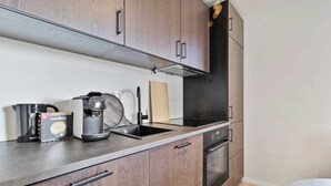 Eine moderne Küche mit Holzausstattung, einem schwarzen Kühlschrank, einer Kaffeemaschine und einer Packung GIMOKA Kaffee.
