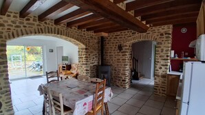 Ein rustikaler Essbereich mit Steinwand, Holzbalken, Fliesenboden und einem Tisch mit Stühlen.