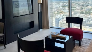 A modern living room with a large window, a flat-screen TV, and a city view. - Sedra Global Hotel Jeddah (Jeddah)