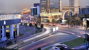 Una intersección urbana moderna con edificios altos, una glorieta y cielo despejado.