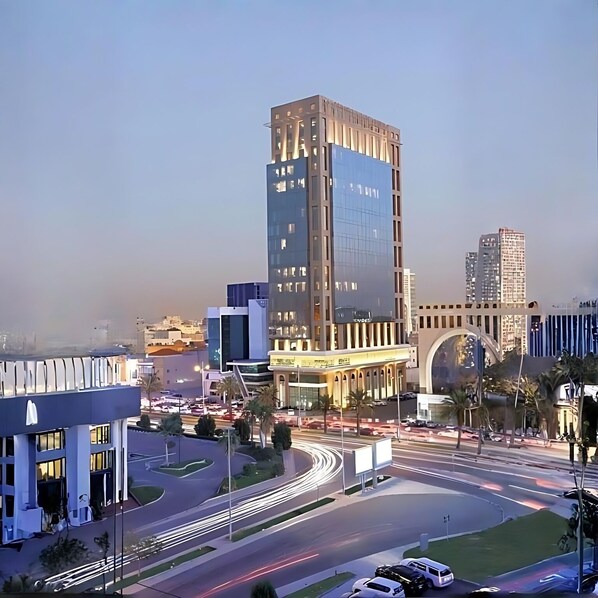 Una intersección urbana moderna con edificios altos, una glorieta y cielo despejado.