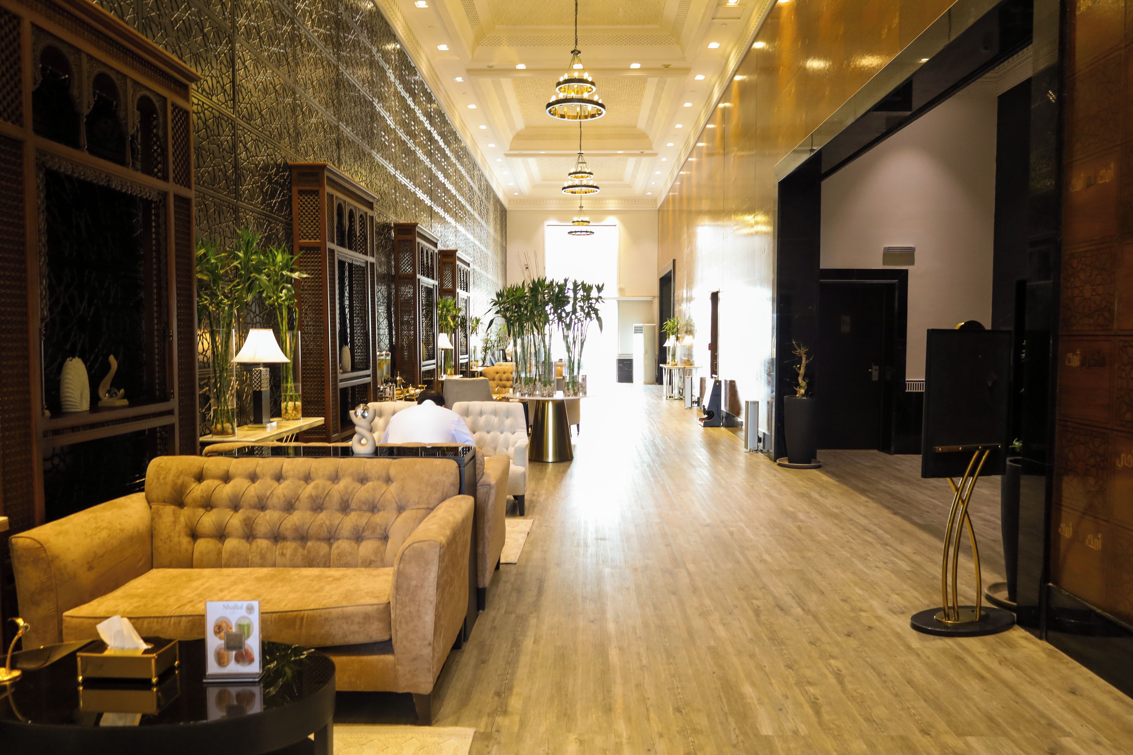 Een hotelhal met een comfortabele bank, een receptiebalie en een decoratieve wand.
