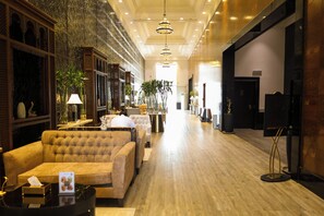 A hotel lobby with a plush sofa, a reception desk, and a decorative wall. - Sedra Al Alami Jeddah Hotel Apartments (Jeddah)