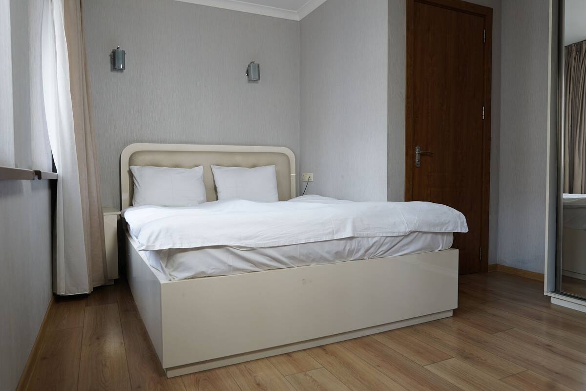 A single bed with a headboard, a bedside table, and a wall-mounted light fixture.