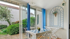 Un patio con una mesa y sillas, una planta colgante y vistas al jardín.