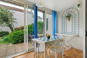 Eine Terrasse mit Tisch und Stühlen, einer hängenden Pflanze und Blick auf den Garten.