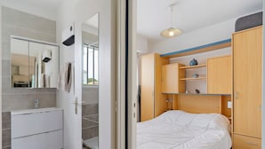 Un dormitorio moderno con cama, armario y baño con espejo y lavabo.
