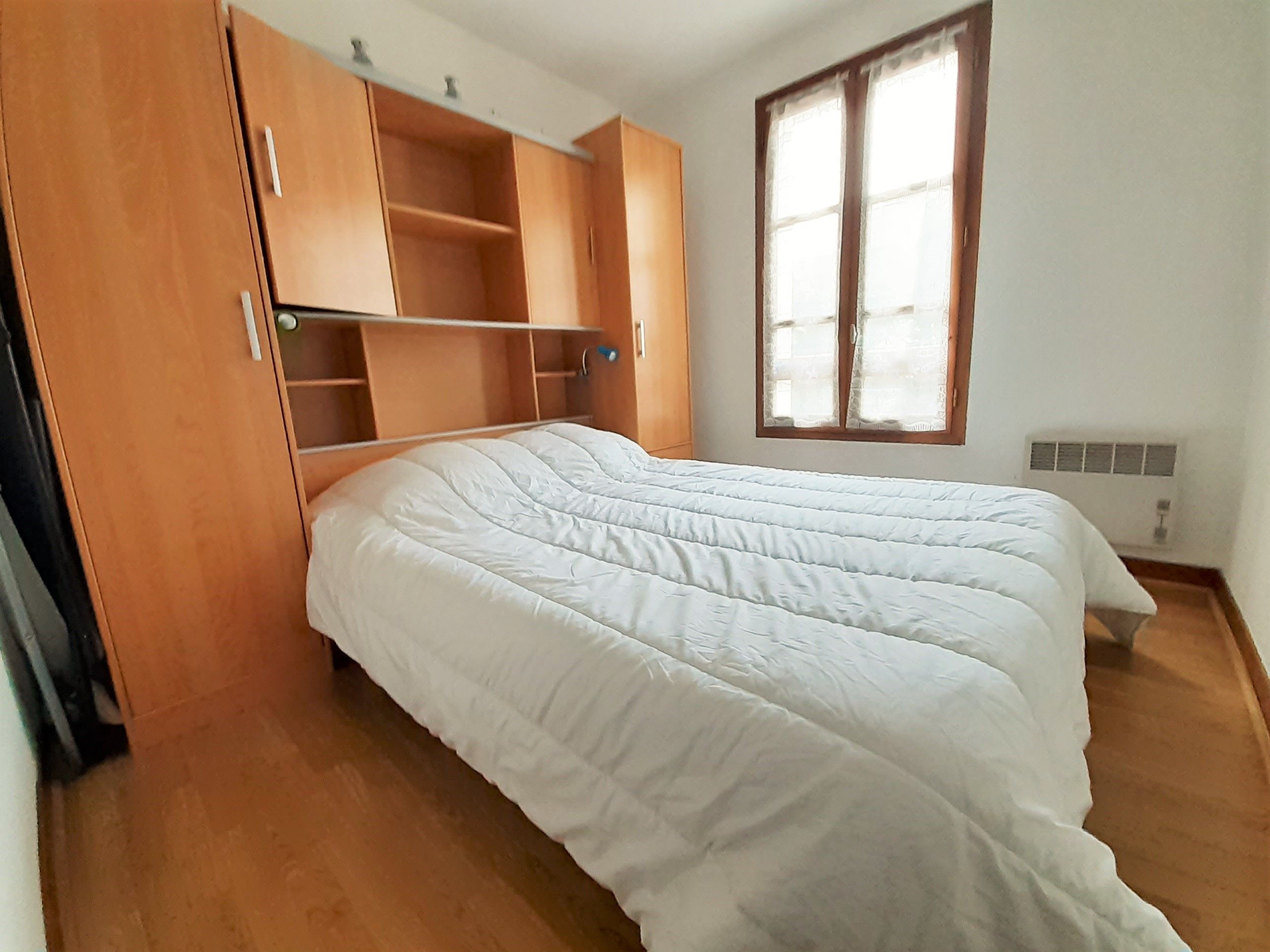 Une chambre à coucher avec un lit, une armoire en bois et une fenêtre.