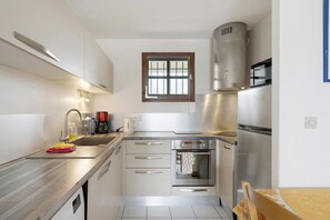 A modern kitchen with stainless steel appliances, a window, and a built-in oven. - Apartment "Les Orphies" with Private Terrace, Shared Garden and Wi-Fi (Vaux-sur-Mer)