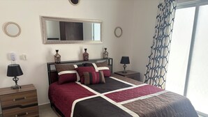 Un dormitorio con una cama grande, dos mesitas de noche, un espejo y una ventana con cortinas.